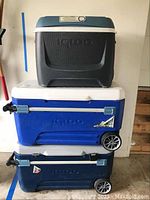 Three stacked Igloo coolers showing default view with visible wheels, lids, and sizes.
