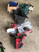 Overhead shot of compressor hose in box and black bag containing tools on garage floor