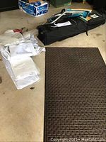 Folded outdoor carpet with square pattern, folded white canopy fabric, and other accessories in a garage setting.