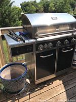 Front view showing entire grill, side burner and storage cabinet doors