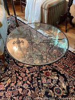 Top view of round clear glass tabletop showing wrought iron scrollwork underneath.