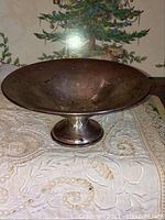 Side and angled view of tarnished sterling silver candy dish on white embroidered cloth, with Christmas tree in background
