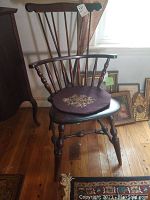 Full front angle of the dark wood Windsor chair showing the floral seat cushion, curved armrests, and back spindles.