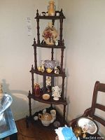 Full view of wooden corner curio shelf with five shelves and decorative finials, holding various decorative items (not included). Shows scratches and wear.