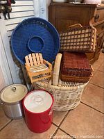 Photo showing the various woven picnic baskets of different sizes and styles including plastic wicker basket, blue woven tray, wooden napkin holder shaped like a chair, and two metal ice buckets.