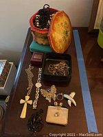 Photo of assorted costume jewelry on table including necklaces, pins, rings, and jewelry boxes