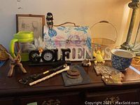 Wide view of all items on dark wood surface including pitcher, floral box, clock, and various figurines.