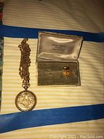 Overview of pocket watch, chain and cuff link on striped cloth