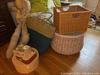 Two large baskets including a round basket with broken handle and a rectangular basket. Two straw beach tote bags and two outdoor seat cushions are also visible. Several small storage boxes and a photo album are in view.