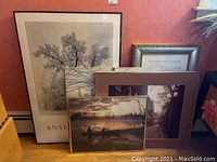 Multiple framed prints and photographs leaning against wall including large Ansel Adams print and other photographic prints