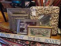 Multiple framed art pieces; includes shell mirror frame, picture frames, and wooden plaque with text.
