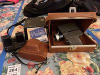 Group photo showing all items: Sawyer ViewMaster, Kodak Pony 828 camera with brown leather case, Crestline Super 8 camera in brown suede carrying case, and reels with instructions.