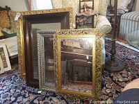 Four mirrors leaning against a wall on a carpeted floor, showing overall condition and frame details.