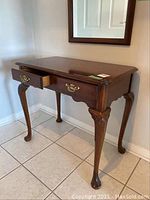 Front perspective view of Strathroy wooden console table showing one drawer open, carved legs and claw feet.