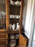 Multiple Tranquility pattern pieces in wooden cabinet: plates, cups, mugs