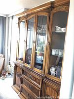 Front view of the full China cabinet with glass doors and shelves, displaying some dishware inside.