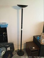 Full view of the black torchiere floor lamp with round base and upward-facing bowl shade on top.