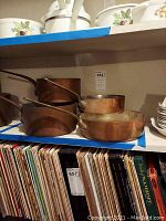 Shelf view showing stock pot on left, medium saucepan and shallow pan in front