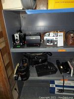Shelf with Polaroid Automatic 600 camera, Kodak Brownie camera, and other vintage cameras with cases.