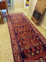Full view of rectangular carpet runner laid on floor showing floral and geometric pattern with worn condition.