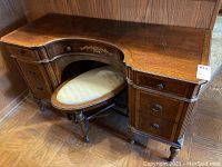 Front view of wooden vanity/desk with oval bench under the curved desk area