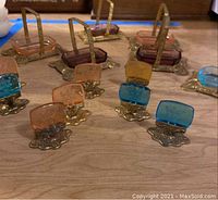 Overview of salt cellars and place card holders showing four metal-framed glass cellars and multiple colored glass card holders.