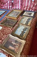 Overview of six framed pieces arranged on red patterned cloth