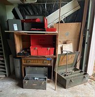 Overall lot showing wooden table, wooden crate, and stacked red metal toolboxes; gray toolbox open with socket set