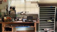 Wide shot showing wooden workbench with tools and metal shelf to the right in garage window light