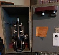 Microscope in open carrying case showing device and its adjustment knobs