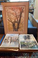 Framed autumn tree limited edition signed wall art print with five loose oil paintings on a table beneath it