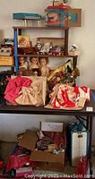 Shelf displaying vintage dolls, doll clothes, astrology book, dishes, boxes with doll accessories and toy sewing machine.