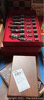 Close-up of metal chess pieces in red box, displaying full row of pawns and major pieces for extended detail.