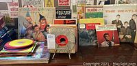 Photo showing multiple vinyl records in sleeves, including colorful children's records and classic LPs from Columbia label.