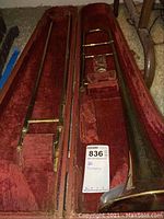 Open trombone case showing interior padded compartments holding the trombone components including the bell, slide, and mouthpiece area.