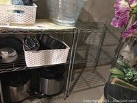 Side view of two metal wire shelving units placed next to each other in basement area with some items stored on adjacent shelving.