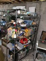 View of entire shelving unit showing multiple tiers filled with painting and crafting supplies including paint containers, trays, tote bags, and assorted small tools.