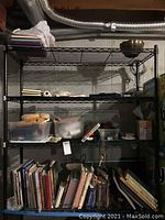 Wide shot of metal shelving with books, containers of crafting supplies, and tools stored on shelves.
