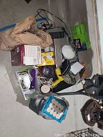 Photo showing various items including a boxed Caruso Professional steam hairsetter, multiple cords, a small cooler, and miscellaneous electronic and household items scattered on the floor.
