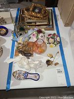Overview of assorted ceramic floral and fauna decor pieces on a white surface, including vases and small framed pictures.