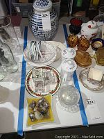 Wide view showing ginger jar, small plates, glassware, salt and pepper shakers, and other assorted décor items on table.