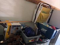 Photo showing Wagner Power Roller box, blue helmet, plastic bins with automotive supplies, small items, and folded folding chairs.