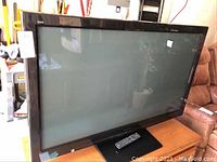 Front view of the 50 inch Panasonic HDTV on stand with remote on top.