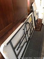 View of several folded white plastic top utility tables with gray metal legs, stacked against a wooden surface.