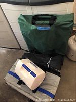 Green folding garden cart folded up on floor with other items