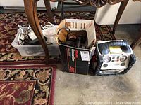 Full view of the lot showing the Skil circular saw box, Itec power source device, and a bin of electrical cords and timers on the floor.