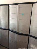 Front view of three beige plastic storage cabinets with black top and middle trim, closed doors.