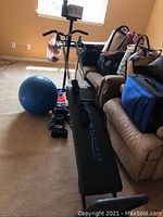 Full view of Total Gym Platinum exercise equipment with incline bench, black padded gliders, and a blue exercise ball beside it.