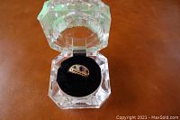 9K gold ring with amethyst stones displayed in faceted clear presentation box with black velvet interior.