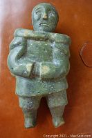 Front view of green soapstone Inuit carving on leather background